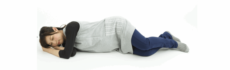 腰痛の悪化を防ぐために、仰向けから一度横向きになってから安全に起き上がる方法を説明した実際の写真